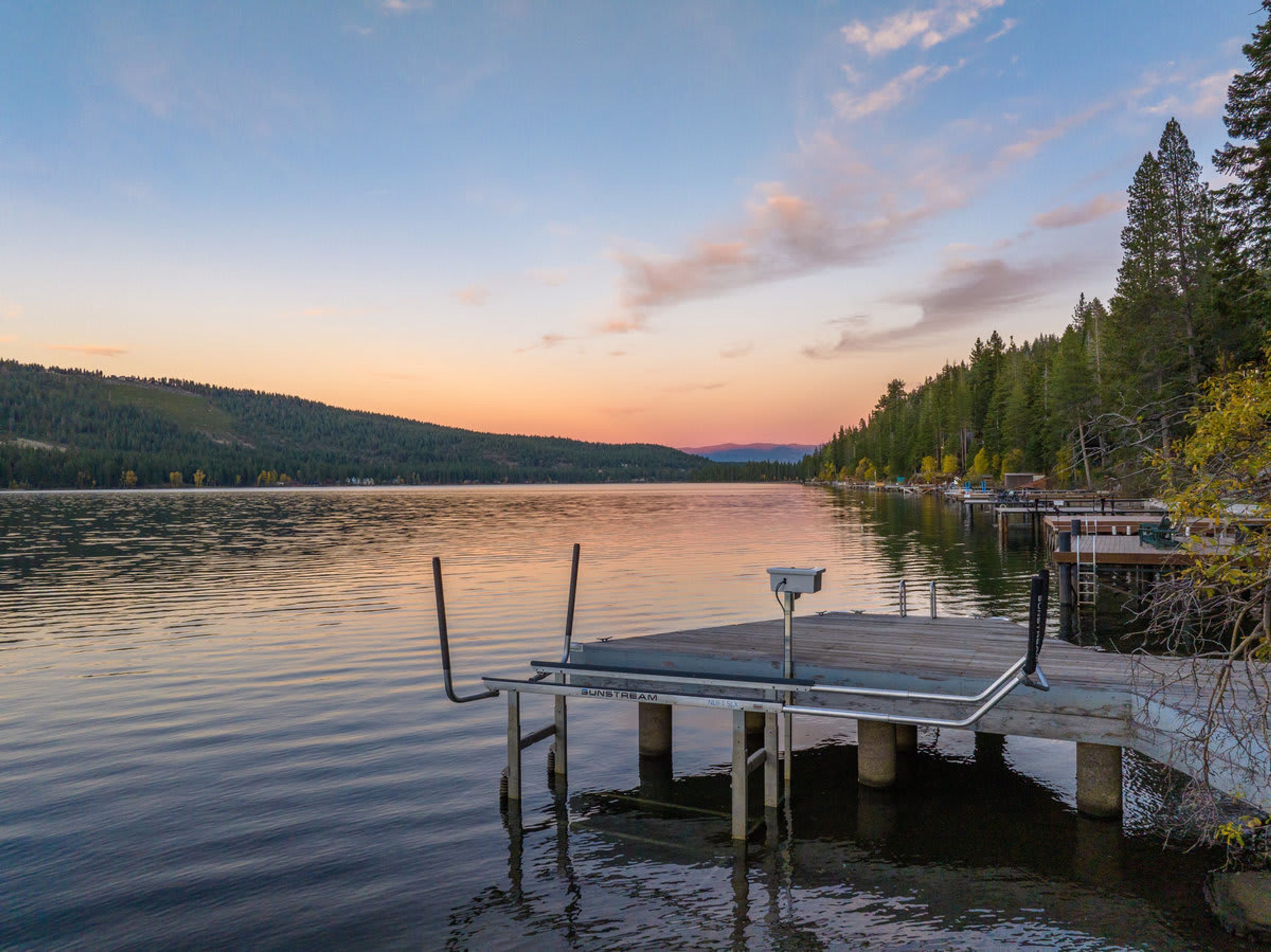 A calm lake with a dock and a boat moored at the pier.