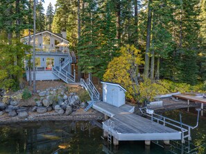A cabin with a dock and a small boat, surrounded by trees and a body of water. - Donner Lake Retreat Hot Tub Game Room (Truckee)