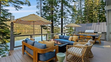 A deck with outdoor furniture, including sofas and chairs, and two striped umbrellas.