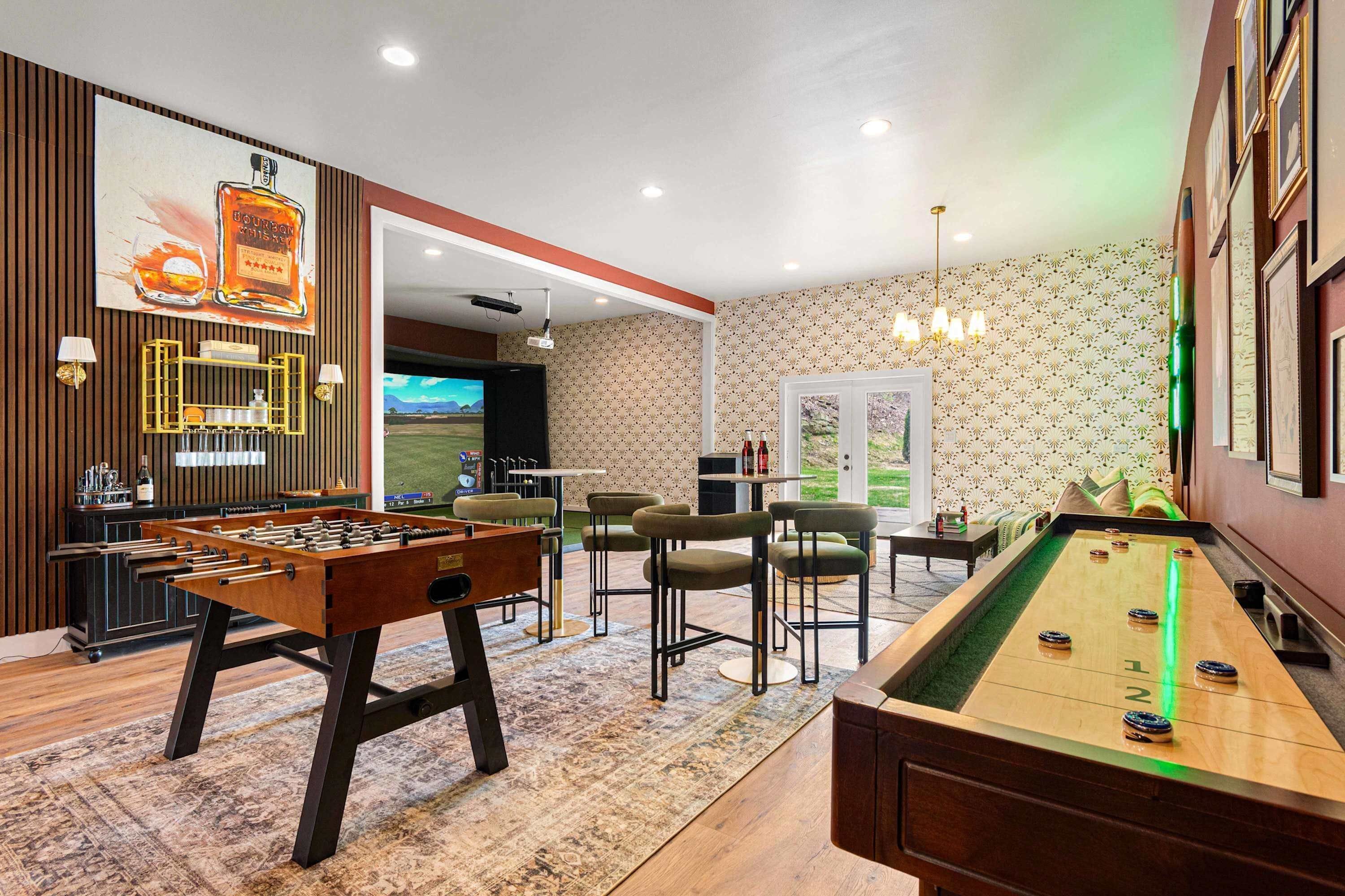 Een kamer met een tafelvoetbaltafel, pooltafel, bar en een televisiescherm waarop een sportwedstrijd wordt vertoond.