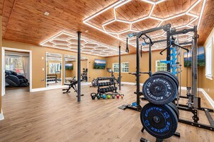 Un gimnasio con suelo de madera, equipo de ejercicio y un diseño de techo hexagonal.