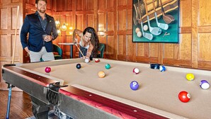 A pool table with balls, a man and a woman standing beside it, and a framed picture of golf clubs on the wall. - 14k sq ft Mountaintop Estate - Private Golf Course (Fletcher)