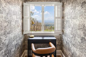 Una habitación con escritorio, una silla y ventana con contraventanas.