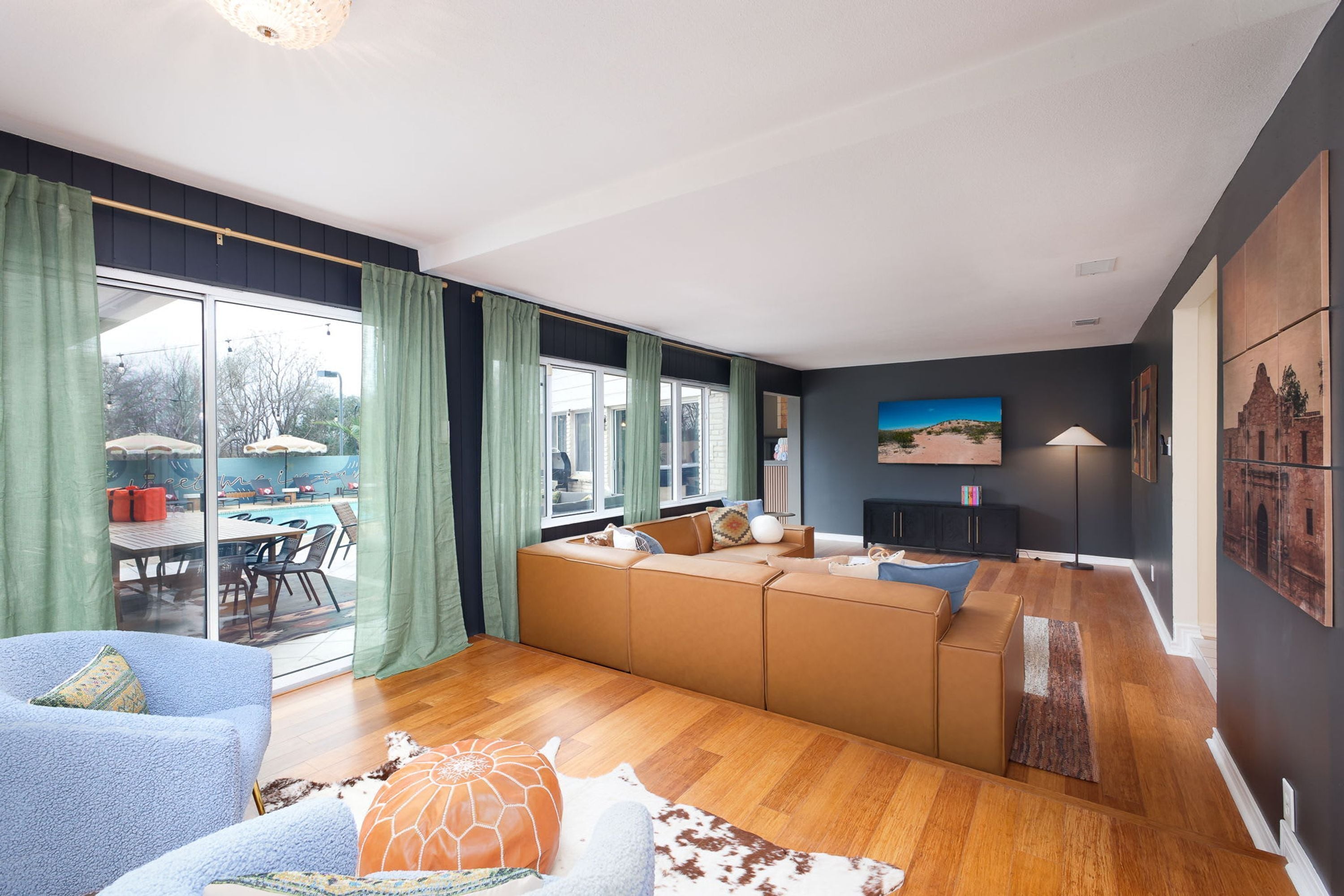 Ein modernes Wohnzimmer mit einer Sofagarnitur, einem Essbereich mit Tisch und Stühlen sowie einem Blick ins Freie durch große Fenster.