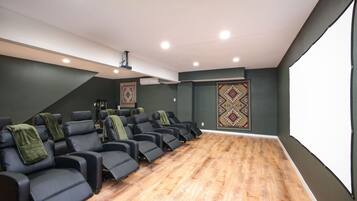 Ein Heimkino mit mehreren Liegesesseln, einer großen Leinwand und einem Teppichboden.