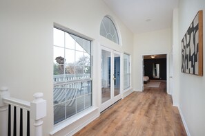 A hallway with wooden flooring, large windows, and a view of the outdoors. - Huge Pickleball Mansion Sleeps 26 Pool Hot Tub (San Antonio)