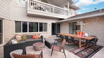 Ein überdachter Patio-Bereich mit Esstisch, Stühlen, einer Couch und einer Feuerstelle.