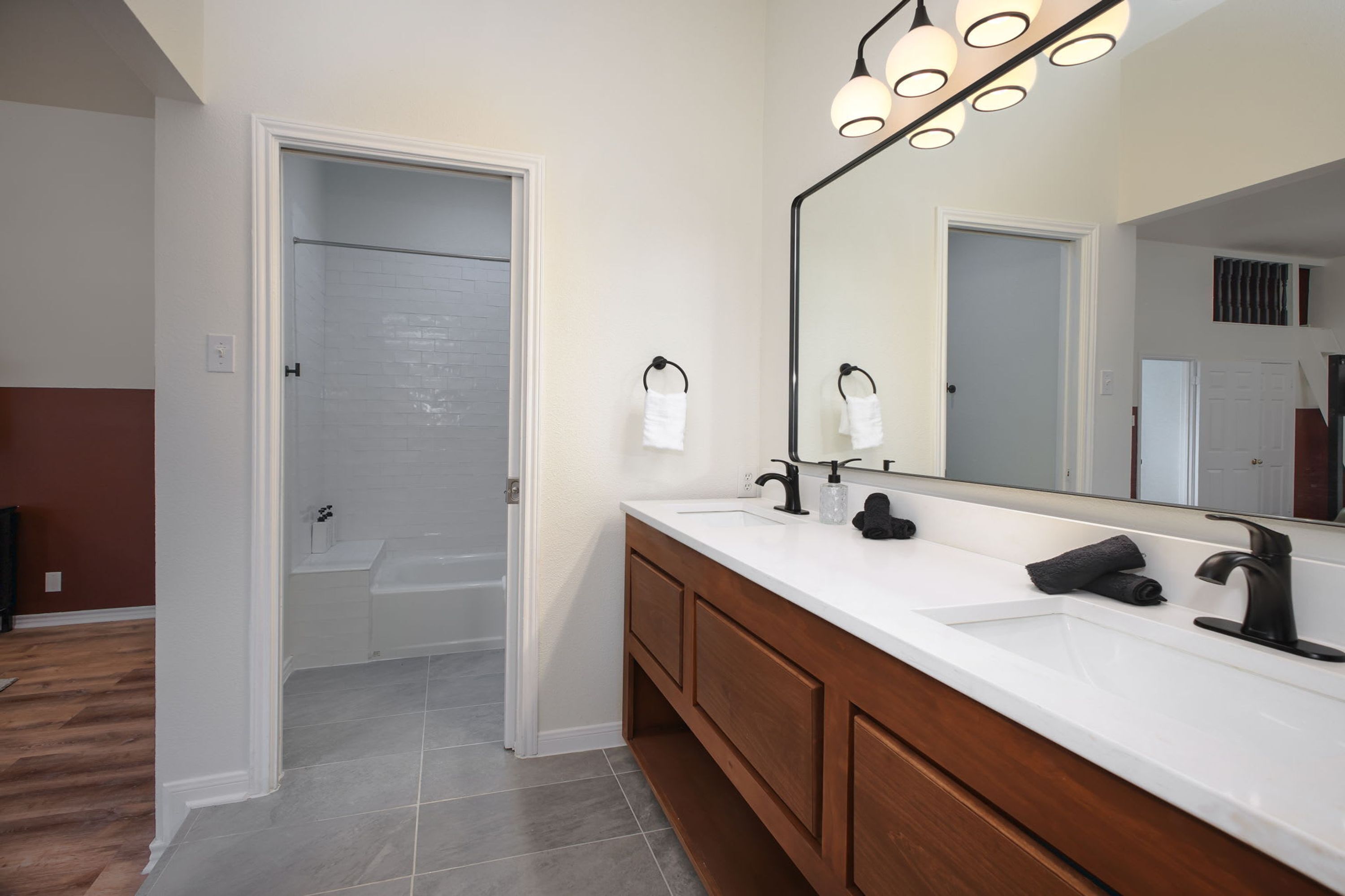 Une salle de bain avec un meuble-lavabo blanc, un grand miroir et un espace douche.