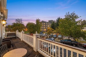 A deck with outdoor furniture, a view of a parking lot, and buildings in the background. - Near Forest Park Central West End - Sleeps 6 (St. Louis)