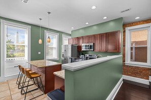 A modern kitchen with a central island, stainless steel appliances, and a view of the city through large windows. - Near Forest Park Central West End - Sleeps 6 (St. Louis)
