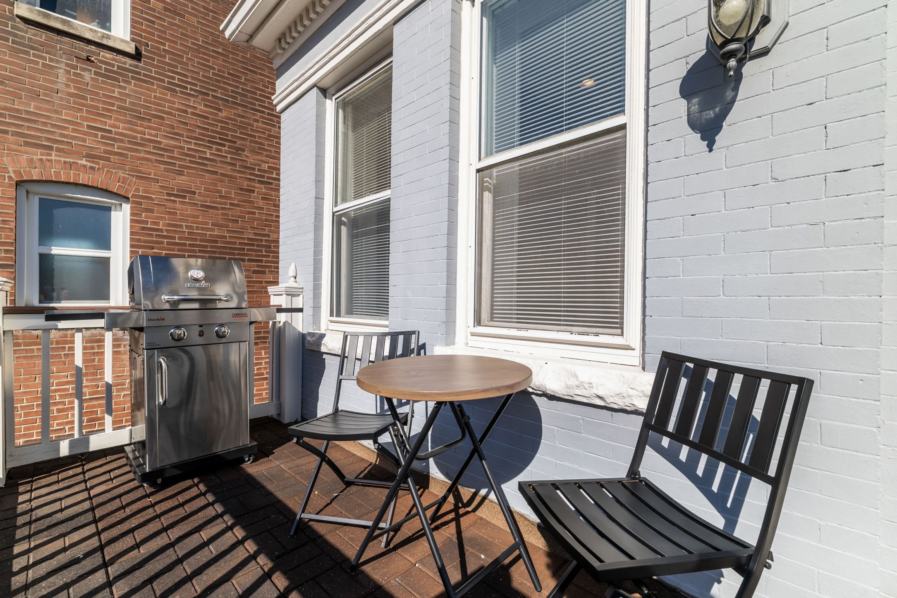 Une terrasse extérieure avec un barbecue, une table et deux chaises.