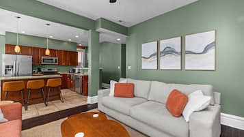 A modern living room with a grey sofa, orange cushions, and a wooden coffee table.