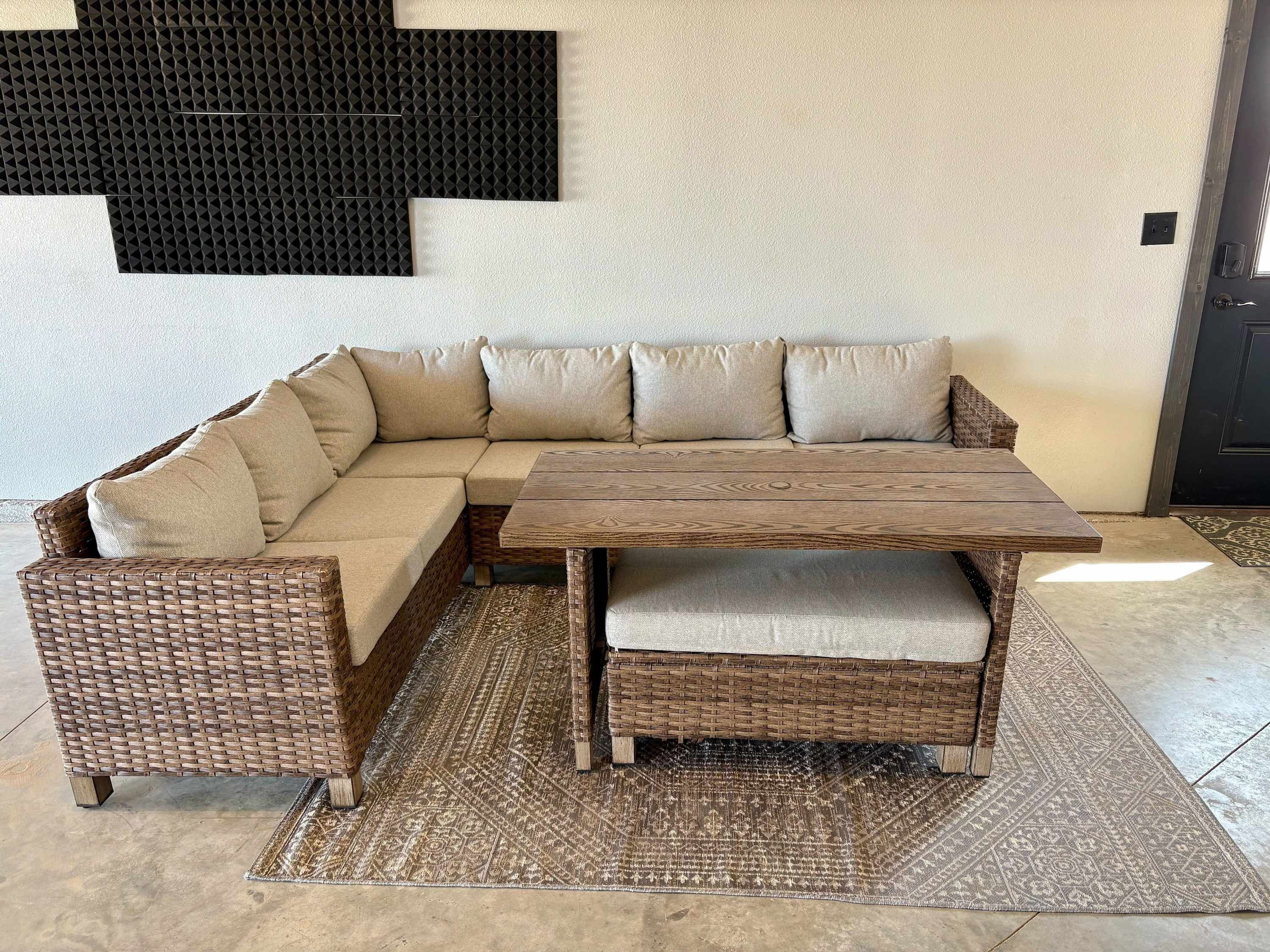 A corner sectional sofa with a matching bench, a wooden coffee table, and a patterned rug on a tiled floor.