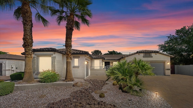 A residential area with two houses, each with a garage, surrounded by palm trees and a gravel driveway. - HTD Pool Fire Pit Games Dog Friendly Ping Pong (Chandler)