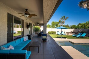 A covered outdoor area with a pool, seating, and a view of the backyard. - HTD Pool Fire Pit Games Dog Friendly Ping Pong (Chandler)