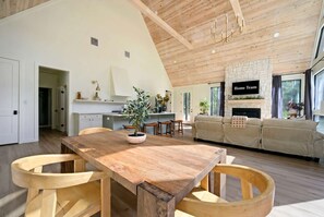 Un amplio salón con una mesa de comedor de madera, un sofá y una chimenea.