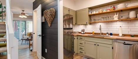 A modern kitchen with light green cabinets, a stainless steel refrigerator, and a heart-shaped wall decoration.