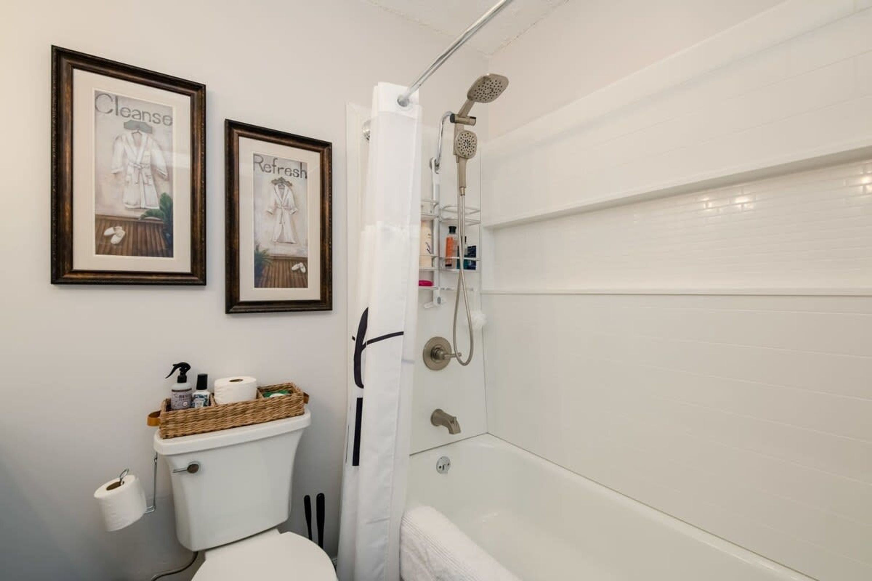 Een badkamer met toilet, een bidet, douche en twee afbeeldingen in lijsten aan de muur.