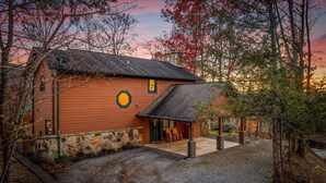 A rustic cabin with a stone foundation, a wooden exterior, and a porch with outdoor seating. - The Smoky Mountain Sanctuary Gym Sauna (Gatlinburg)