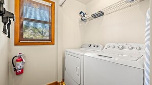 A laundry room with a dryer, a wall-mounted heater, and a fire extinguisher. - The Smoky Mountain Sanctuary Gym Sauna (Gatlinburg)