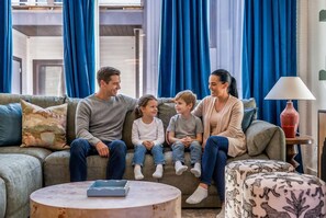 A family sitting on a couch in a living room with a round coffee table in front. - 4BR Nashville Hideaway - Rooftop Views - Fire Pit (Nashville)