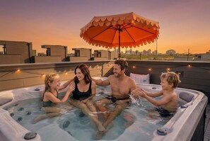 A rooftop hot tub with an umbrella, surrounded by a city skyline at sunset. - 4BR Nashville Hideaway - Rooftop Views - Fire Pit (Nashville)