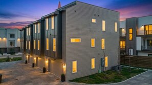 A modern multi-story residential building with a flat roof, multiple windows, and a well-lit exterior. - 4BR Nashville Hideaway - Rooftop Views - Fire Pit (Nashville)