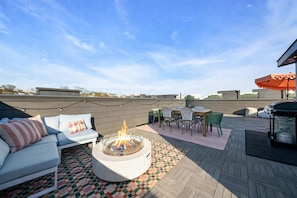 Um terraço no telhado com lareira, móveis de exterior e vista para o horizonte da cidade.