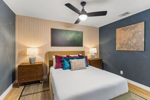 A bedroom with a bed, two nightstands, a ceiling fan, and wall art. - Cowboy Luxe Retreat Pool Putt Putt Pickleball (San Antonio)