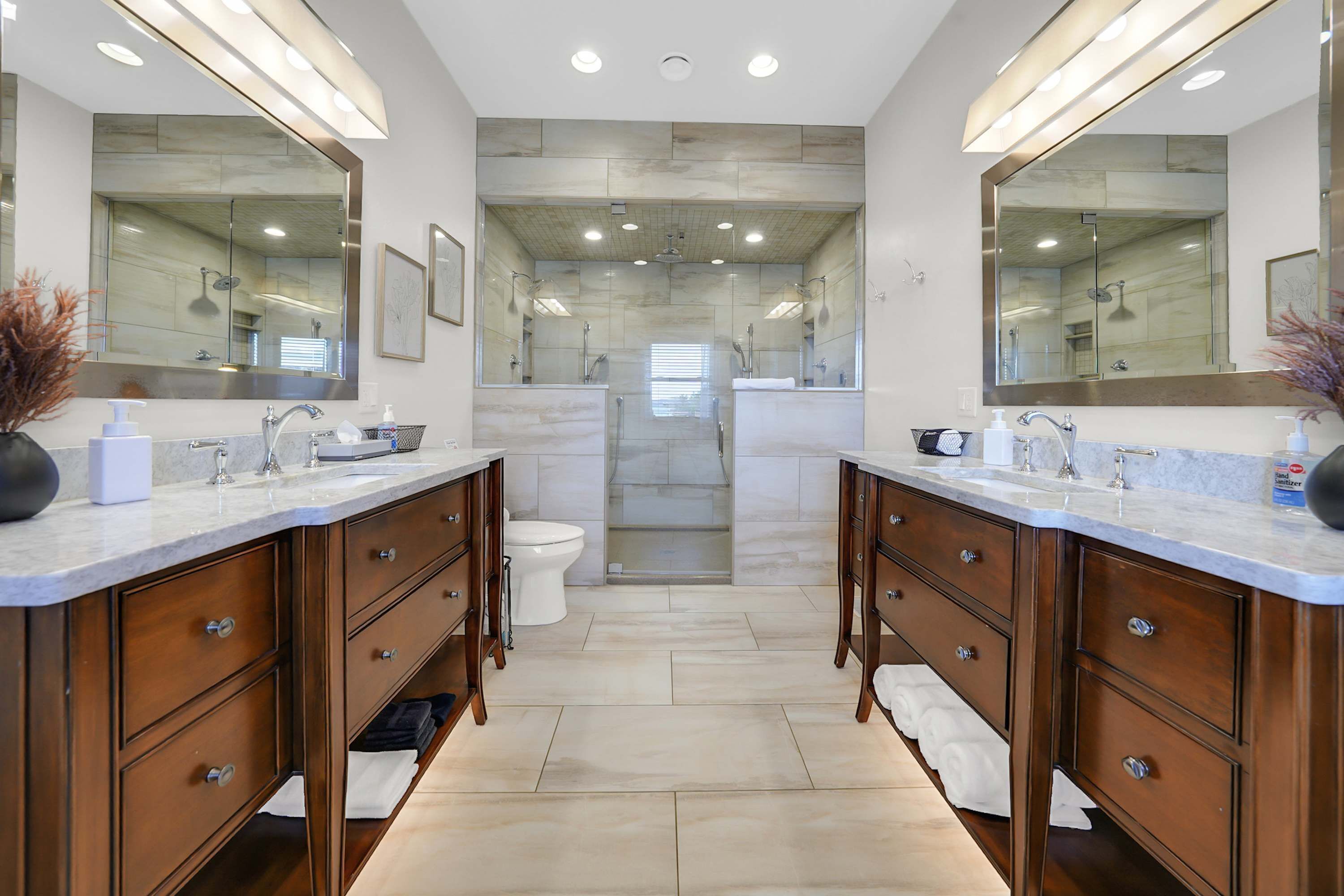 A modern bathroom with dual sinks, a shower, and a toilet.