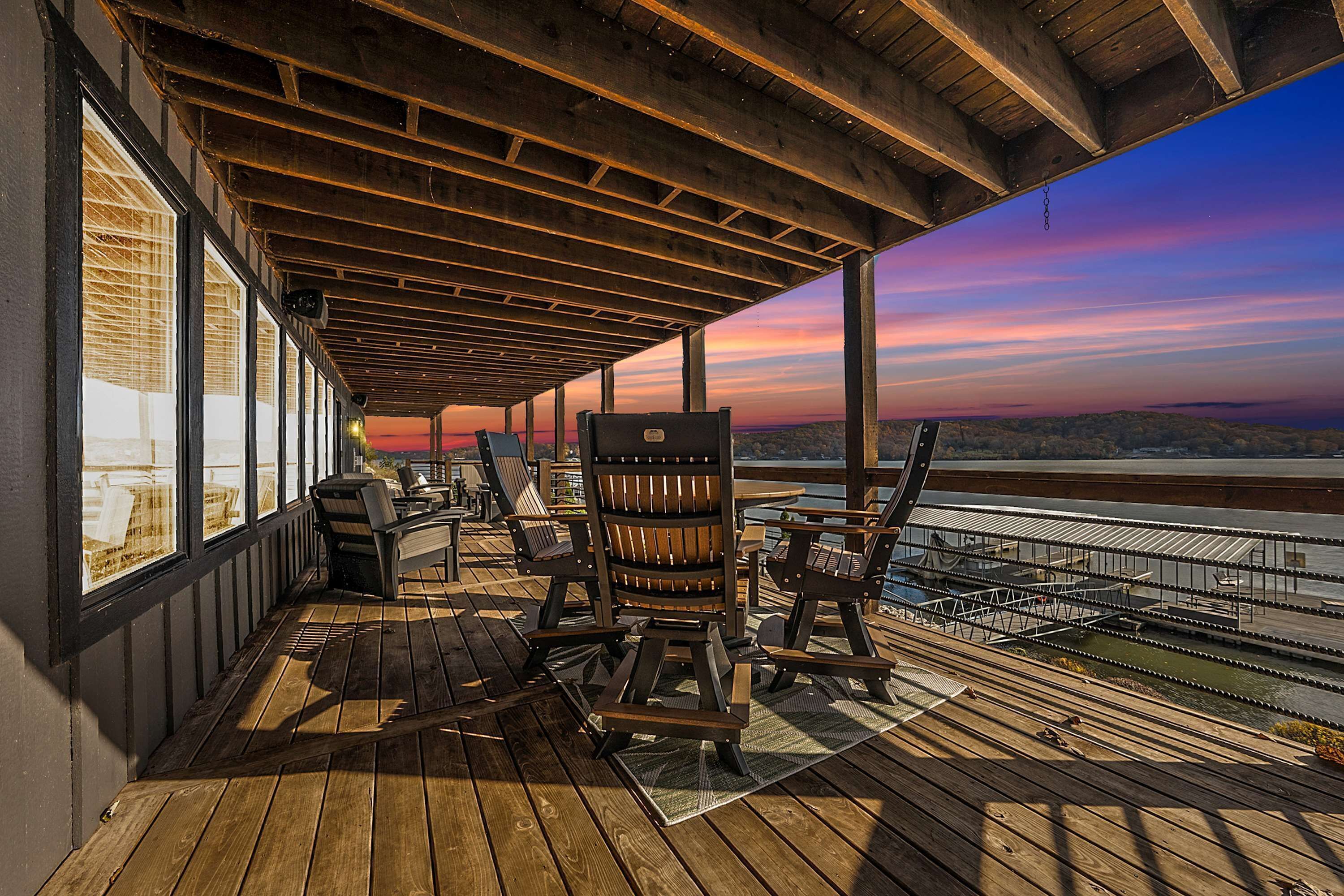 Eine überdachte Terrasse im Freien mit Holzmöbeln und Blick auf das Wasser.