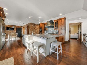 A modern kitchen with a central island, wooden cabinets, and a brick accent wall. - Sunrise Beach Private Dock Pool (Sunrise Beach)