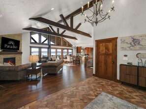 A spacious living area with a fireplace, leather sofas, a herringbone floor pattern, and a chandelier. - Sunrise Beach Private Dock Pool (Sunrise Beach)