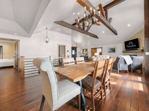 A spacious living area with a wooden dining table, comfortable seating, and a modern chandelier. - Sunrise Beach Private Dock Pool (Sunrise Beach)