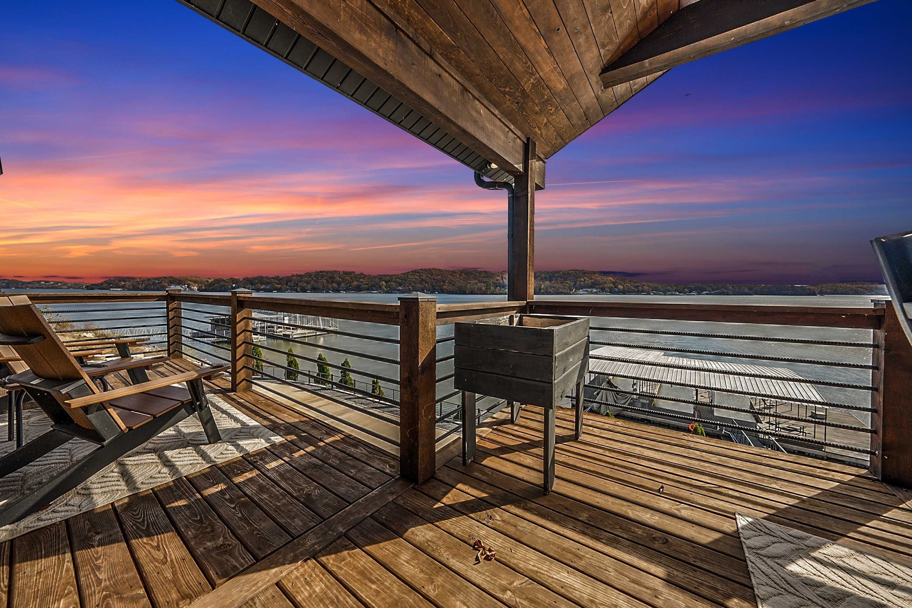 A wooden deck with a railing overlooking a body of water and a distant shoreline.