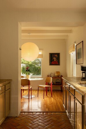 Une cuisine moderne avec un parquet à motifs en chevrons, des chaises en bois, une table ronde et un luminaire suspendu.