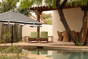 A poolside area with two lounge chairs, a striped umbrella, and a pergola. - The Tucson Bungalow Designer Sam Hughes Retreat (Tucson)