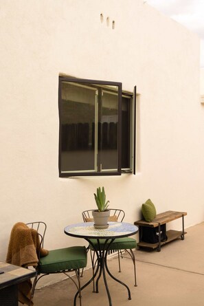 An outdoor seating area with a round table, chairs, a bench, and a potted plant. - The Tucson Bungalow Designer Sam Hughes Retreat (Tucson)