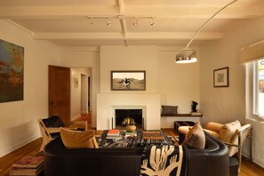 Un salon avec une cheminée, une table basse avec des livres, un canapé et une lampe.