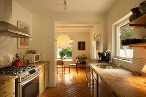 A modern kitchen with a herringbone floor, stainless steel appliances, and a view to the dining area. - The Tucson Bungalow Designer Sam Hughes Retreat (Tucson)