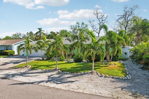 A residential area with a paved driveway, a lawn with palm trees, and a house with a light-colored exterior. - 4 Br Bradenton Home Private Pool Outdoor Bar W D (Bradenton)