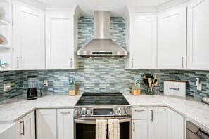A modern kitchen with white cabinetry, a stainless steel range hood, a built-in oven, and a tiled backsplash. - 4 Br Bradenton Home Private Pool Outdoor Bar W D (Bradenton)