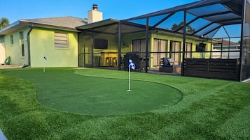 A modern house with a well-maintained lawn and a golf putting area.