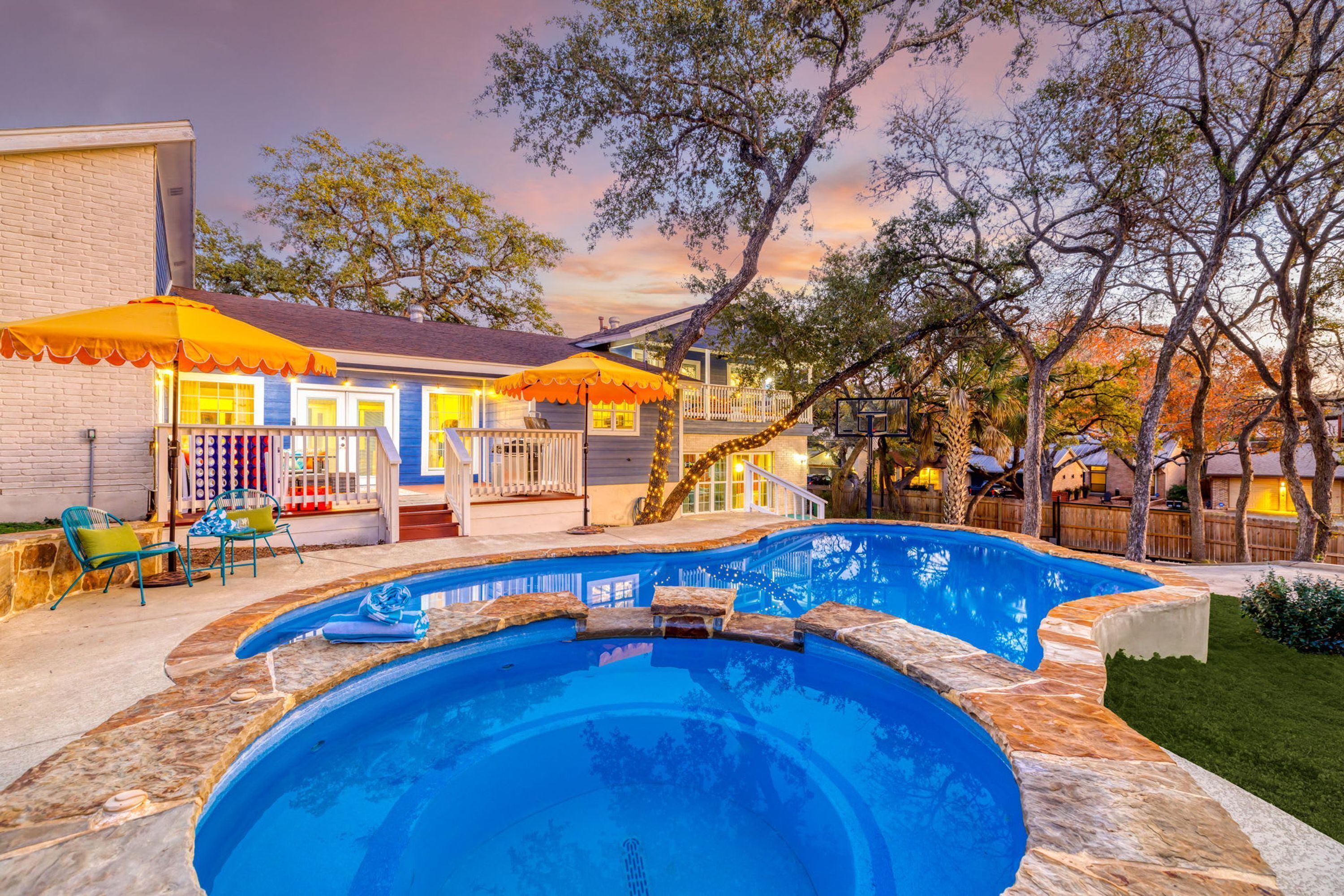 Ein Garten mit Swimmingpool, überdachter Terrasse und einem Haus mit Ziegel Fassade.