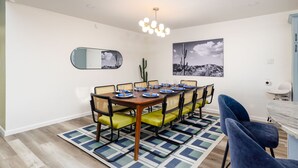 A dining area with a long table, chairs, a chandelier, and a cactus plant. - The Sunburst Sleeps 18 Basketball Heated Pool (San Antonio)