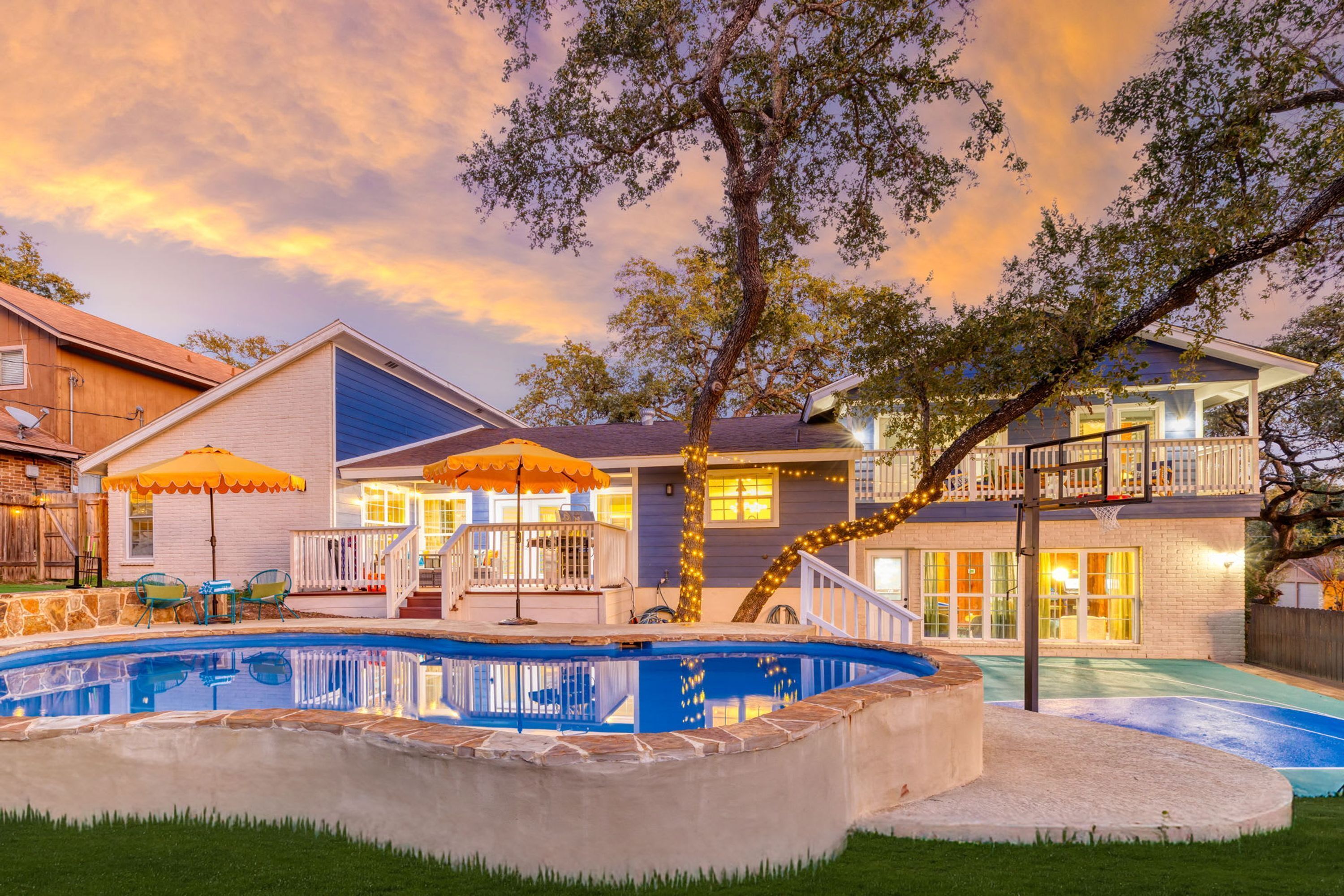 A residential property with a swimming pool, a covered patio, and a two-story house.
