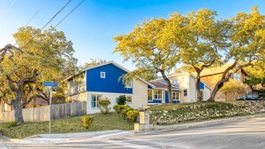 A residential street with houses, a street sign, and a clear sky. - The Sunburst Sleeps 18 Basketball Heated Pool (San Antonio)
