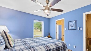 Un dormitorio con cama, ventilador de techo, ventana y puerta.