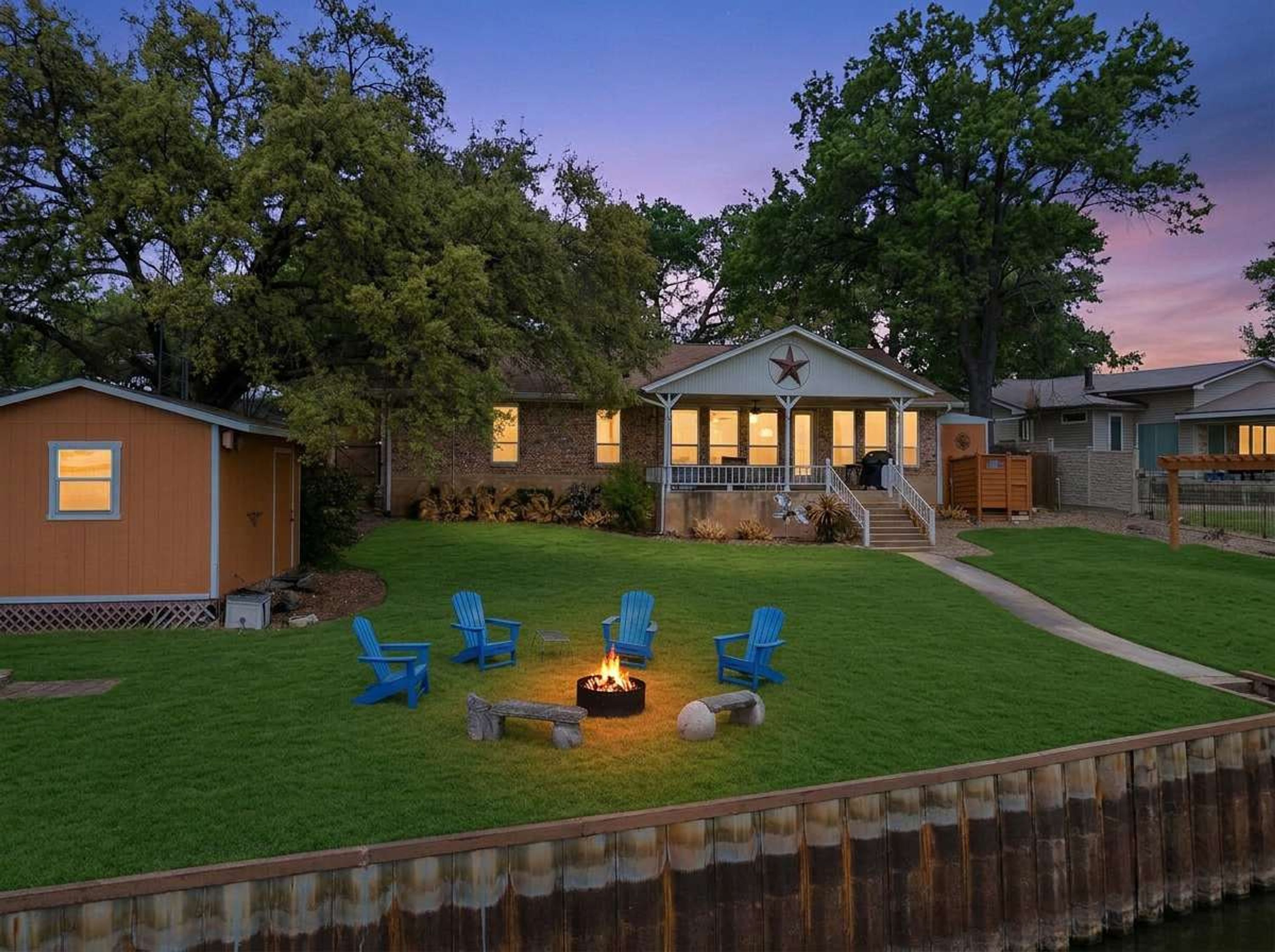 Un patio trasero con una chimenea, mobiliario exterior y una casa con porche.