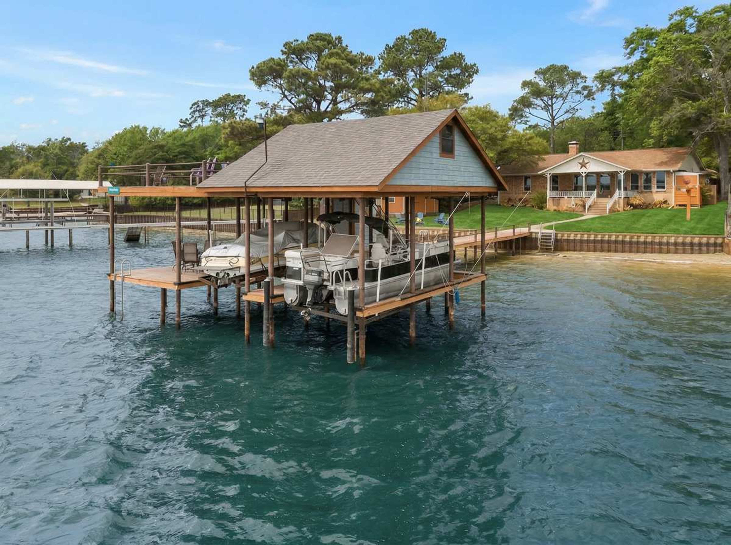 Una propiedad frente al agua con muelle, un barco cubierto y la casa principal.